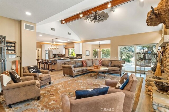 living room featuring beam ceiling, rail lighting, light hardwood / wood-style flooring, high vaulted ceiling, and a notable chandelier