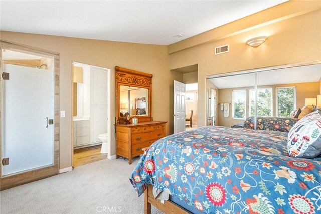 carpeted bedroom featuring lofted ceiling, visible vents, and ensuite bathroom