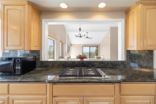 kitchen with pendant lighting, light brown cabinetry, stainless steel gas cooktop, and dark stone countertops