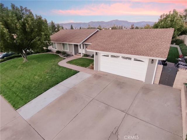 ranch-style home featuring a lawn, a mountain view, and a garage