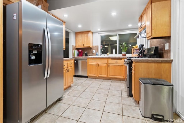 kitchen with decorative backsplash, light brown cabinetry, light tile patterned floors, and stainless steel appliances