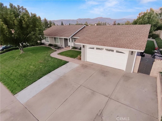 single story home featuring a mountain view, a garage, and a front lawn