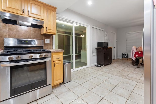 kitchen with decorative backsplash, gas range, light tile patterned floors, and light brown cabinetry