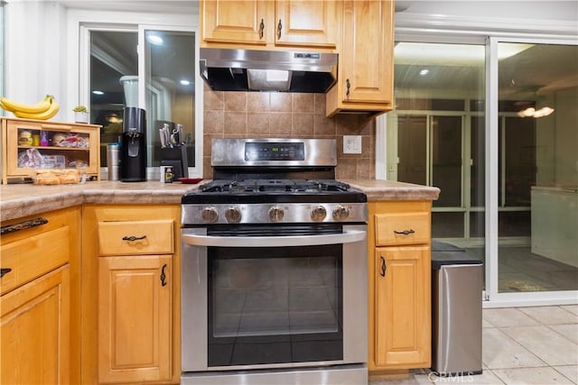 kitchen with decorative backsplash, gas stove, and light tile patterned flooring