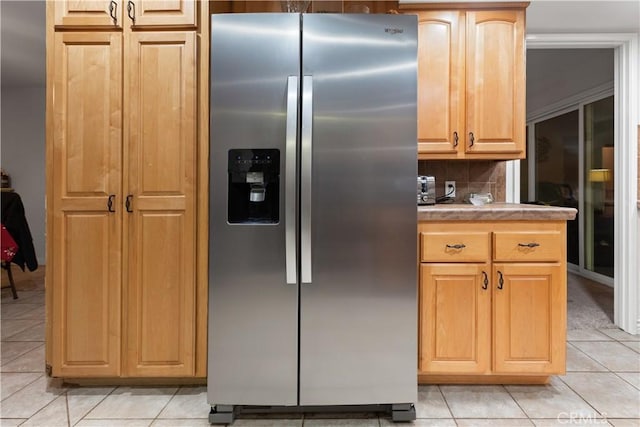 kitchen featuring decorative backsplash, stainless steel fridge, light brown cabinetry, and light tile patterned floors