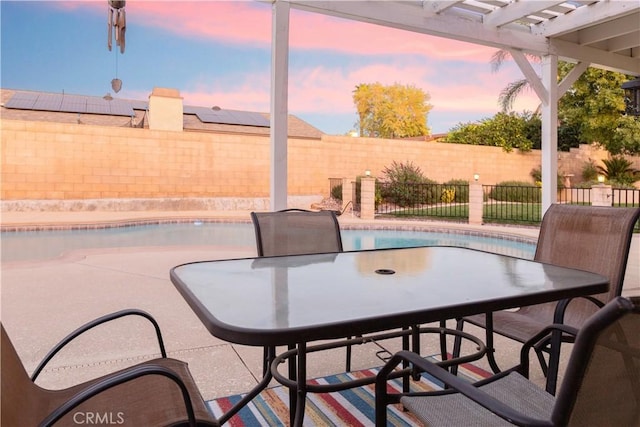 patio terrace at dusk featuring a fenced in pool