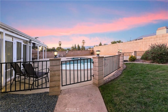 pool at dusk featuring a lawn