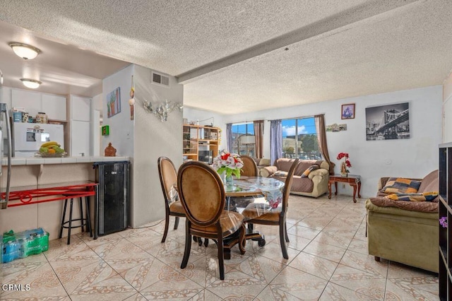 tiled dining area with a textured ceiling and wine cooler