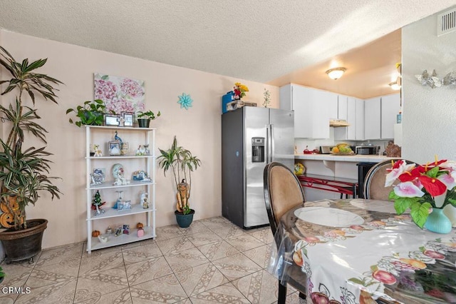 kitchen featuring light tile patterned floors, a textured ceiling, stainless steel appliances, and white cabinetry