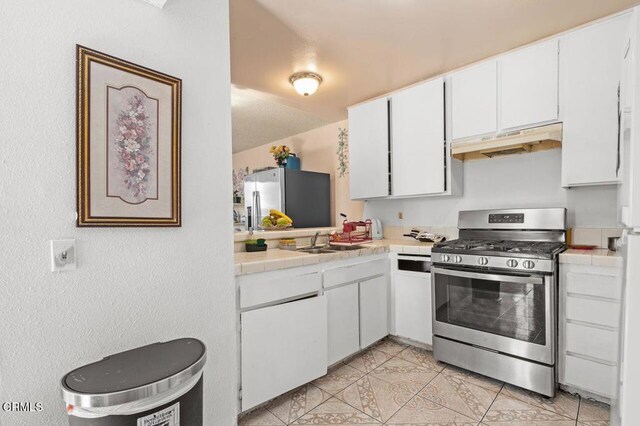 1431 Casa San Carlos Ln Unit A, Oxnard, CA 93033 - kitchen with stainless steel appliances, under cabinet range hood, tile counters, white cabinetry, and light tile patterned flooring