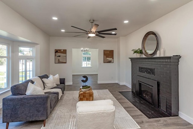 living room with wood-type flooring, a fireplace, ceiling fan, and a wealth of natural light