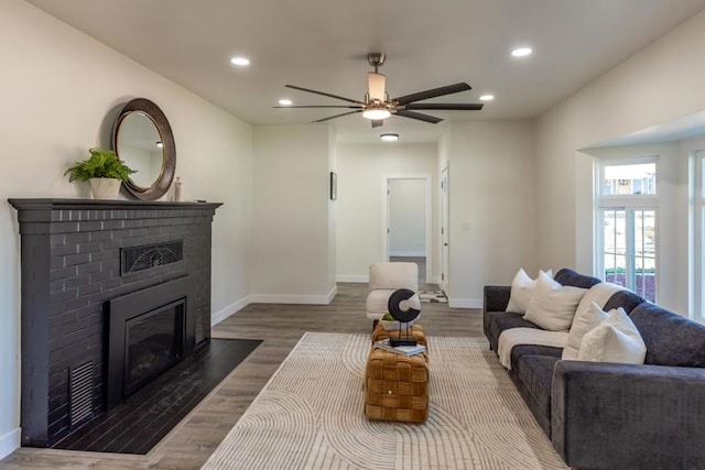 living room featuring ceiling fan, hardwood / wood-style floors, and a fireplace