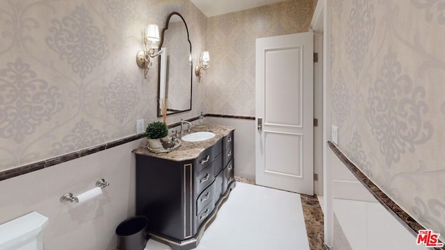 bathroom with vanity, toilet, and tile walls