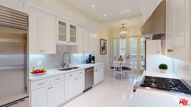 kitchen with sink, decorative backsplash, appliances with stainless steel finishes, island range hood, and white cabinetry