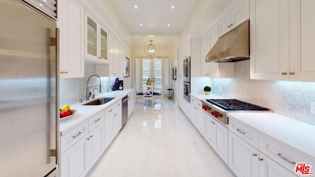 kitchen with backsplash, sink, appliances with stainless steel finishes, decorative light fixtures, and white cabinetry