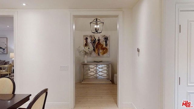 hall with an inviting chandelier and light hardwood / wood-style flooring