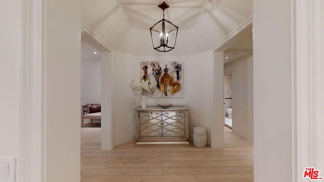 corridor featuring a notable chandelier, lofted ceiling, and light wood-type flooring