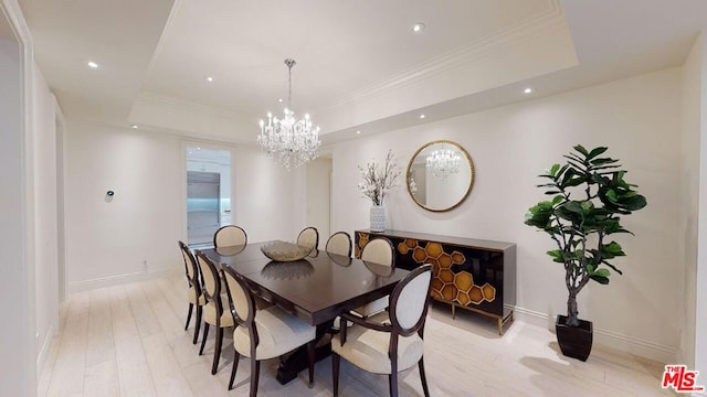 dining space with a tray ceiling, crown molding, light hardwood / wood-style flooring, and a chandelier