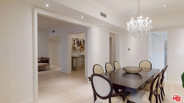 dining room featuring crown molding, light hardwood / wood-style floors, and an inviting chandelier