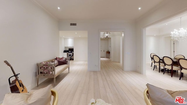 living area featuring light hardwood / wood-style flooring, an inviting chandelier, and ornamental molding