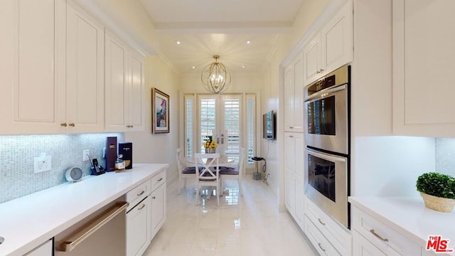 kitchen with decorative backsplash, appliances with stainless steel finishes, decorative light fixtures, an inviting chandelier, and white cabinets