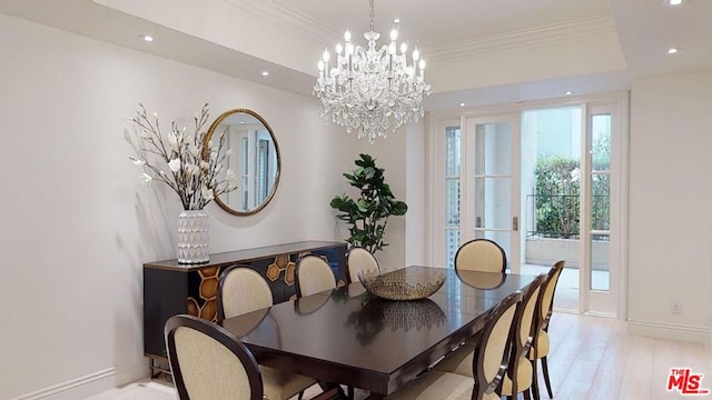 dining room with a raised ceiling, crown molding, light wood-type flooring, and a notable chandelier