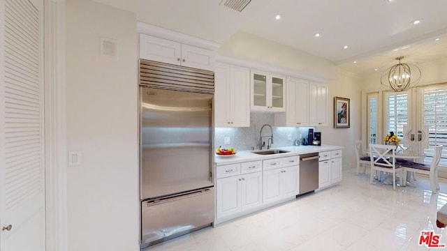 kitchen featuring an inviting chandelier, sink, decorative backsplash, appliances with stainless steel finishes, and white cabinetry