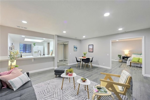 living area featuring light wood-type flooring, baseboards, visible vents, and recessed lighting