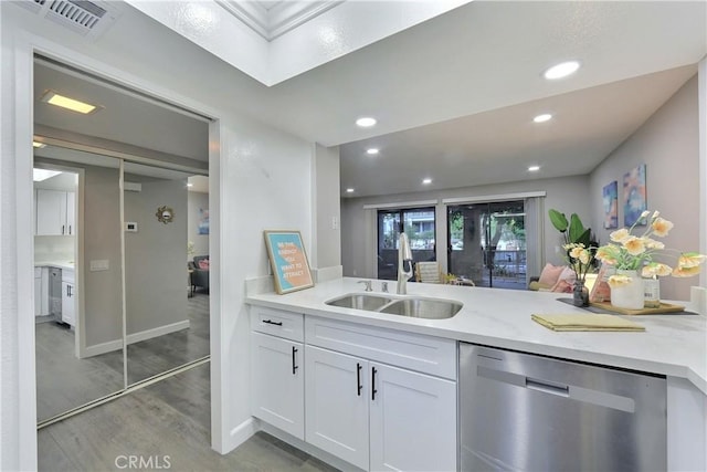 kitchen with visible vents, light wood-style floors, white cabinetry, a sink, and dishwasher