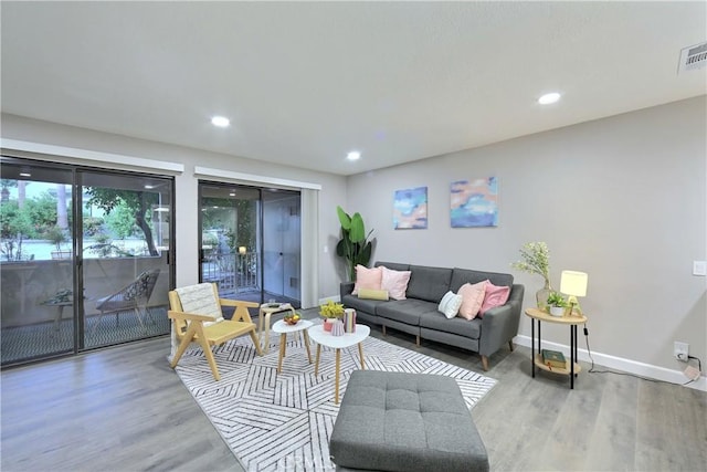 living room with light wood-style flooring, visible vents, baseboards, and recessed lighting