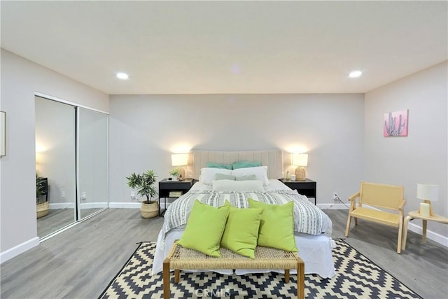 bedroom featuring a closet, baseboards, wood finished floors, and recessed lighting