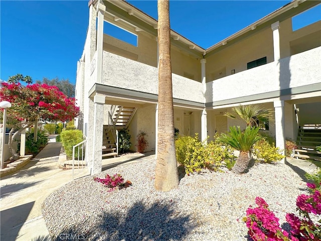 back of property with a balcony, stairway, and stucco siding