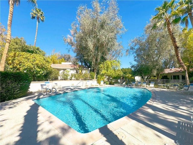 community pool with fence and a patio