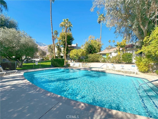 pool with a mountain view, a patio, and fence