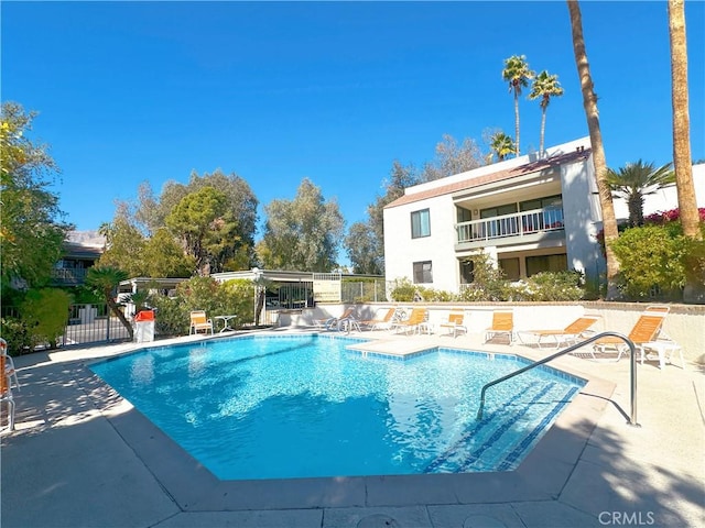 community pool with fence and a patio