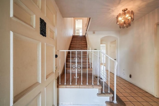 staircase with an inviting chandelier and tile patterned floors