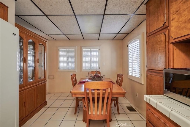 dining room with a drop ceiling and light tile patterned flooring