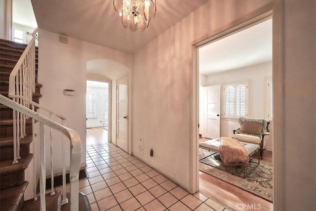 hall featuring an inviting chandelier, a healthy amount of sunlight, and light wood-type flooring