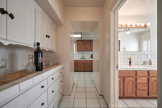 bar featuring tile counters, white cabinetry, light tile patterned floors, and tasteful backsplash