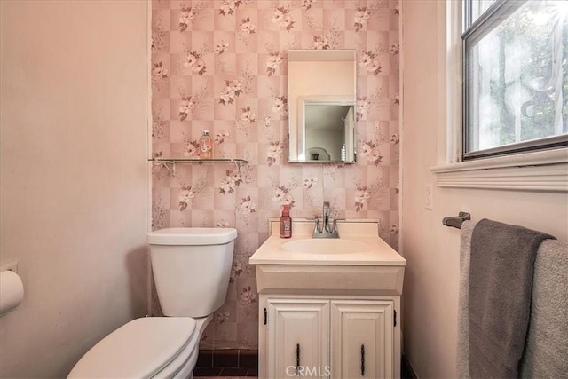 bathroom featuring vanity, a healthy amount of sunlight, and toilet