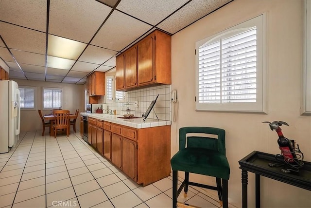 kitchen with a paneled ceiling, dishwasher, a healthy amount of sunlight, and white refrigerator with ice dispenser