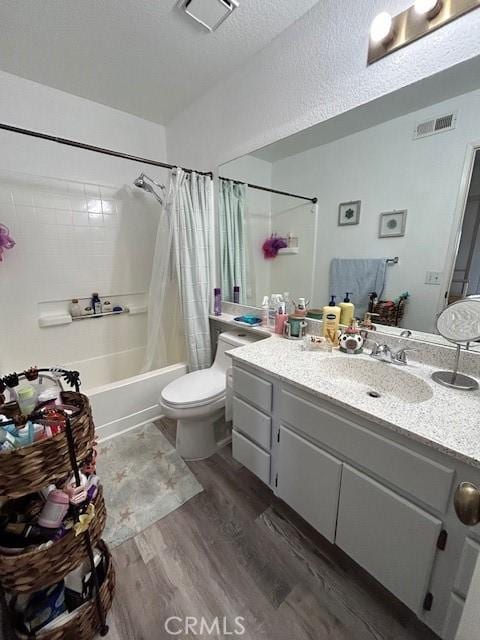 full bathroom featuring shower / bath combination with curtain, vanity, a textured ceiling, hardwood / wood-style flooring, and toilet