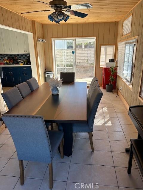 dining space with a wealth of natural light, wooden ceiling, and wood walls