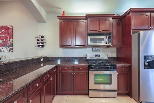 kitchen with light tile patterned flooring, stainless steel appliances, and dark stone counters