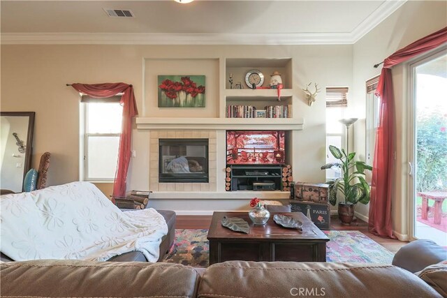 living room featuring a tile fireplace, hardwood / wood-style floors, plenty of natural light, and ornamental molding