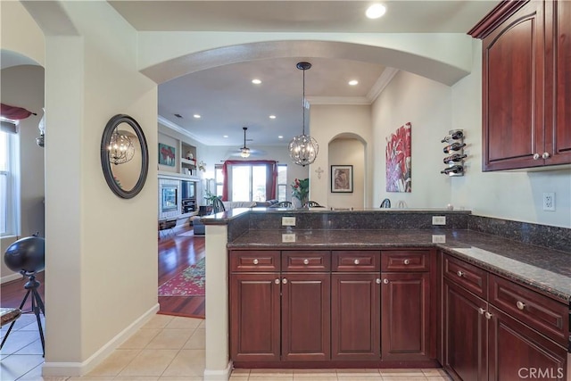 kitchen featuring hanging light fixtures, light hardwood / wood-style flooring, dark stone counters, and ornamental molding