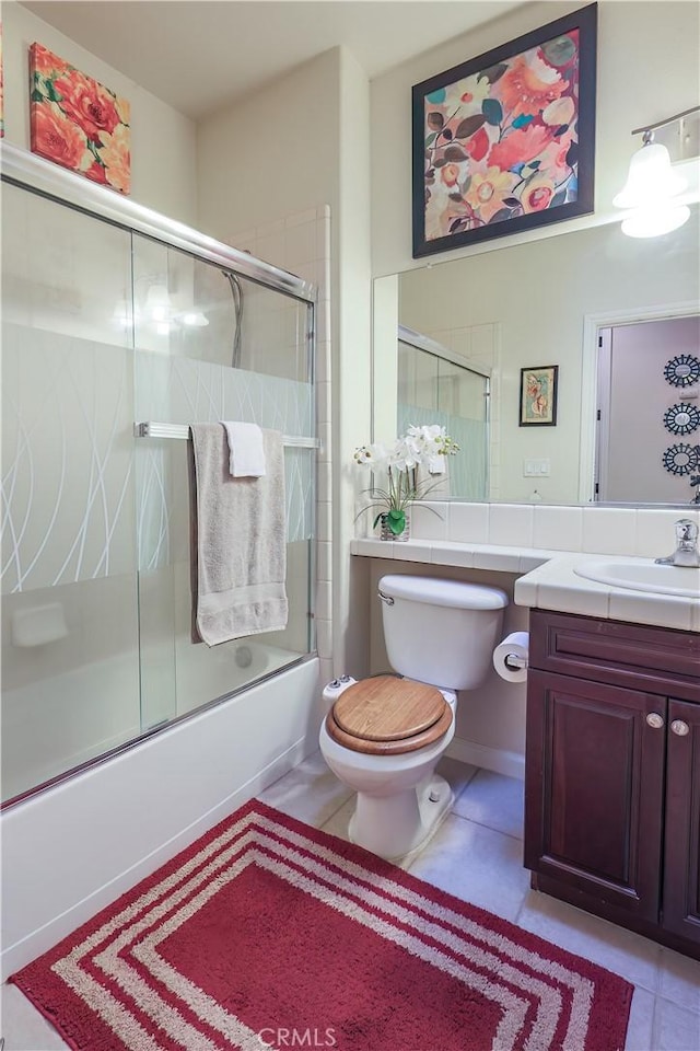 full bathroom with toilet, vanity, tile patterned floors, and enclosed tub / shower combo