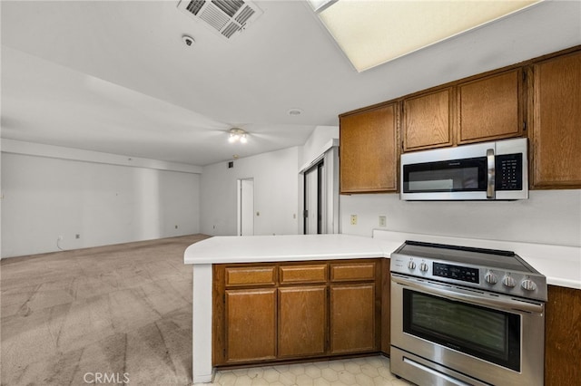 kitchen with light colored carpet, kitchen peninsula, and stainless steel appliances