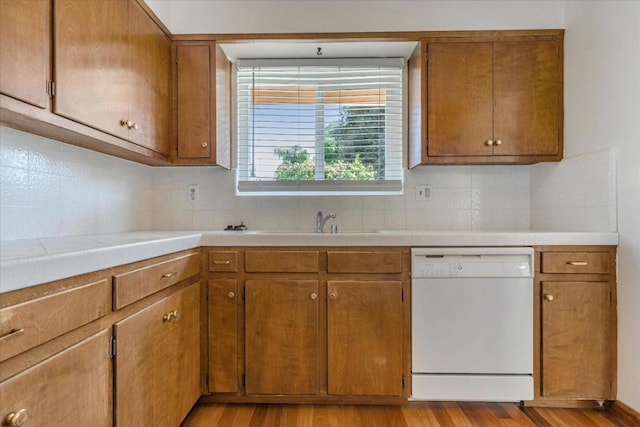 kitchen with light wood-type flooring, backsplash, dishwasher, and sink