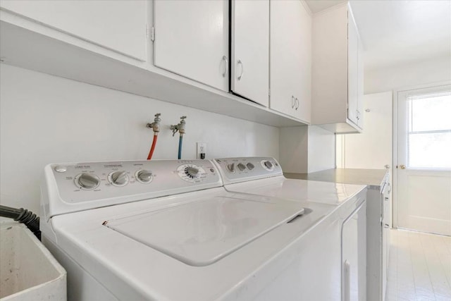 clothes washing area featuring sink, washer and dryer, and cabinets